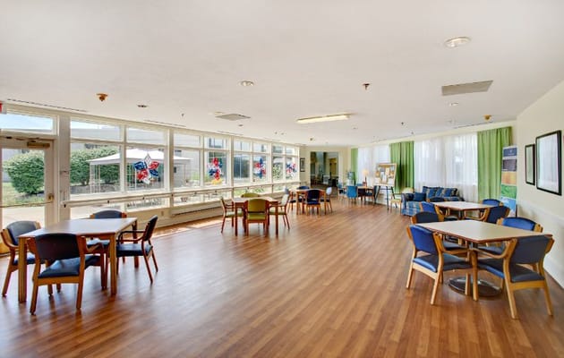 Bright and spacious common area with tables and chairs at Overlook Green Senior Living