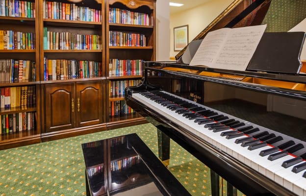 Close-up of a piano and bookshelf in a senior living facility