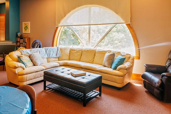 Comfortable lounge with a white sofa and a coffee table near a large arched window.