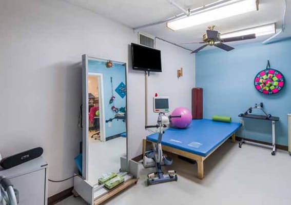 Well-equipped therapy room with exercise equipment and a large mirror