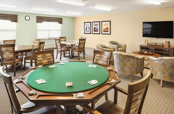 A gaming room with a green poker table and seating at Prairie Green at Dixie Crossing.