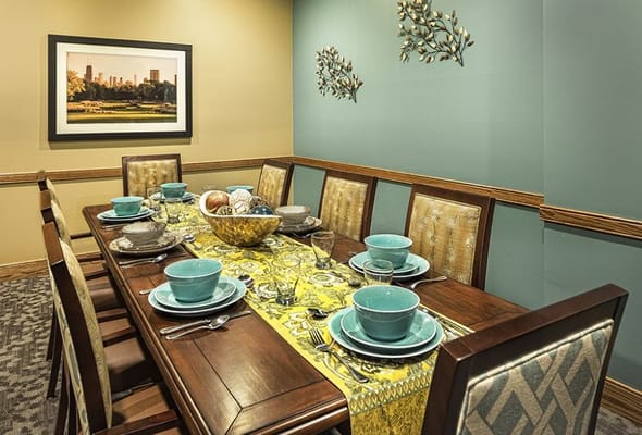 Elegant dining room set with teal dinnerware and a vibrant yellow table runner.