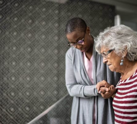 Caregiver assisting an elderly woman indoors