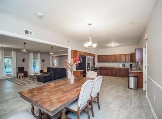 Bright and spacious dining area with wooden table and kitchen