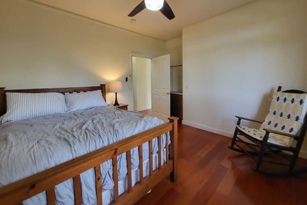 Spacious bedroom with a wooden bed and rocking chair