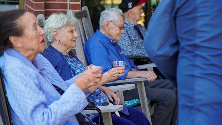 Group of seniors sitting on rocking chairs outdoors