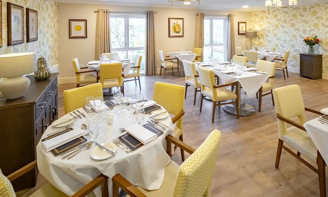 Bright dining area with set tables and chairs at Saxon Manor Care Home