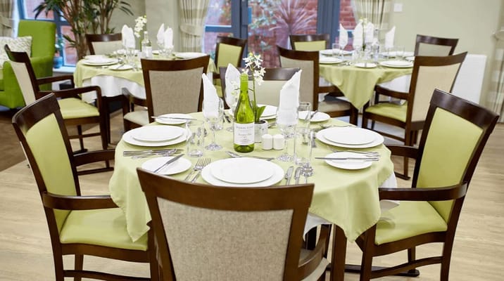 Elegant dining table set with plates and glasses in Scholars Mews care home