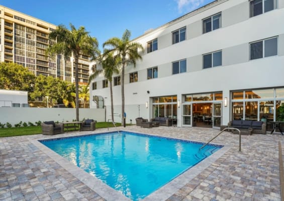 Swimming pool surrounded by lounge chairs and palm trees
