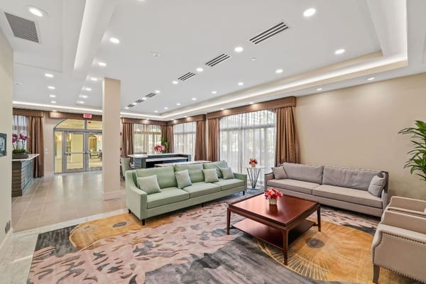 Cozy living room with green and gray sofas in a senior living facility.
