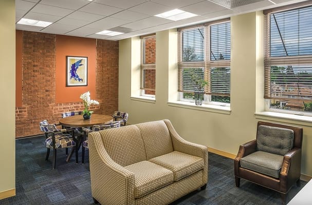 Lounge area with a sofa, chairs, and a dining table near large windows