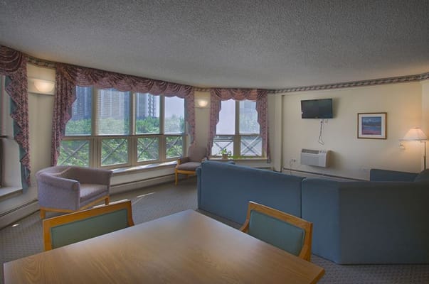 Comfortable living room with a couch, chairs, and a view of the city skyline.