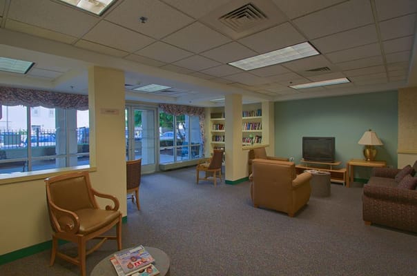 Lounge area with seating and bookshelf in a senior living facility