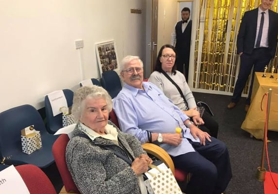 Three seniors sitting together, smiling at a gathering
