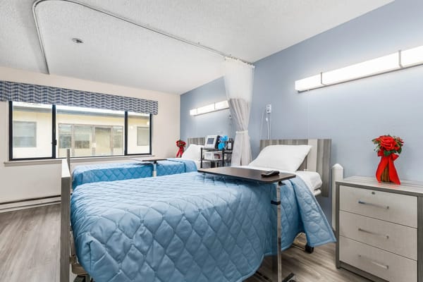 Cozy bedroom with two beds, blue quilts, and a small table