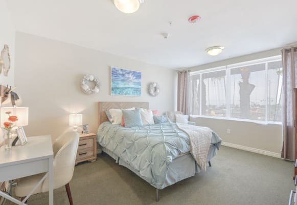 Bright and inviting bedroom with a bed, desk, and window view
