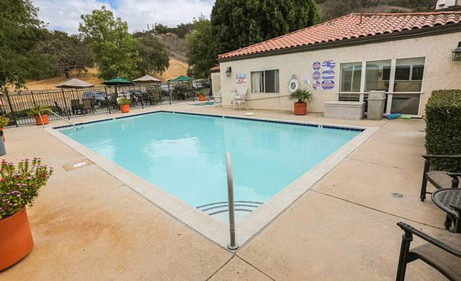 Swimming pool surrounded by lounge chairs and umbrellas