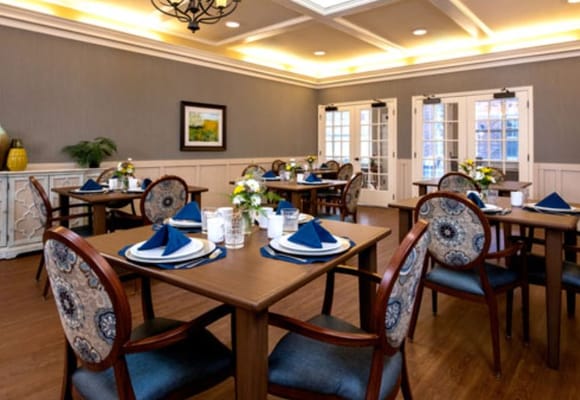 Dining area with elegantly set tables and floral arrangements.