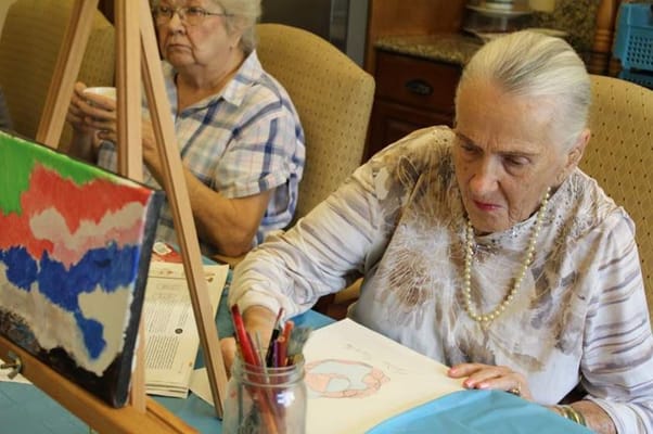 Residents participating in an art activity, one painting and another observing.