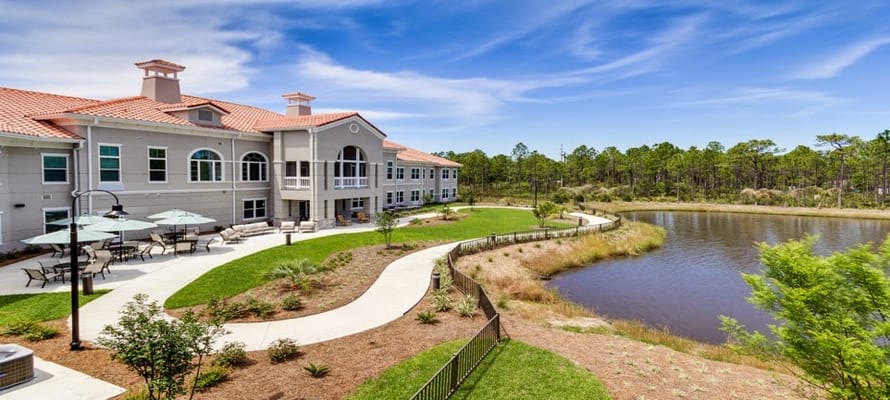 Exterior view of assisted living facility with garden and water