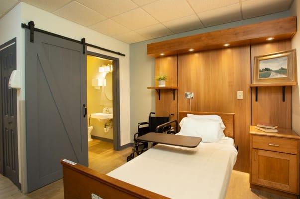 Comfortable private room with a bed and a wheelchair.