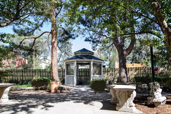 Gazebo surrounded by trees and shrubs in a landscaped area