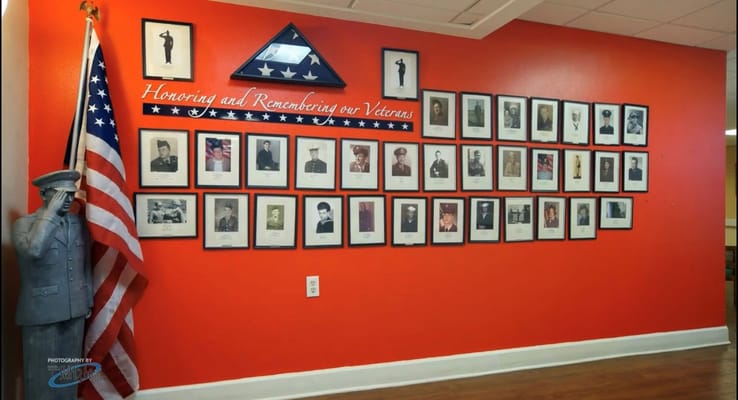 Wall displaying photographs of veterans alongside an American flag.