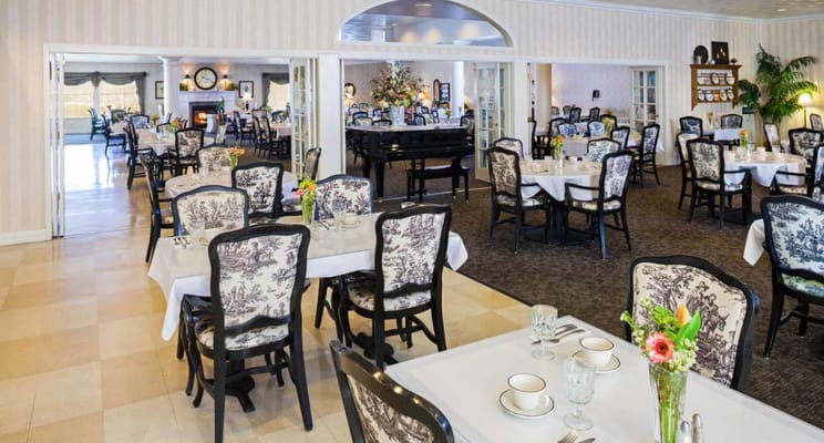 Elegant dining room with floral decorations and tables set for dining.