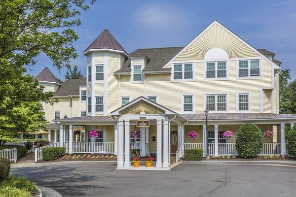 Front entrance of Sunrise at Countryside with flower pots and a welcoming sign.