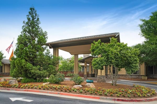 Main entrance of Sunrise at Webb Gin with landscaping and flags