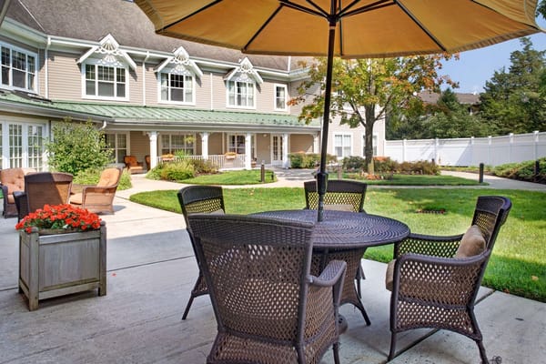 Wicker chairs and table under an umbrella in a garden area