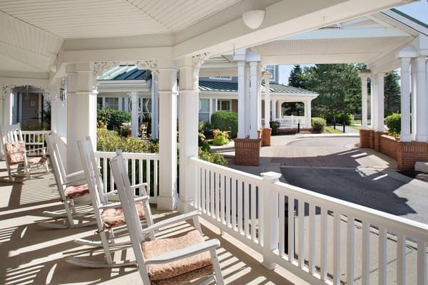Porch with rocking chairs overlooking the entrance of Sunrise of Buffalo Grove