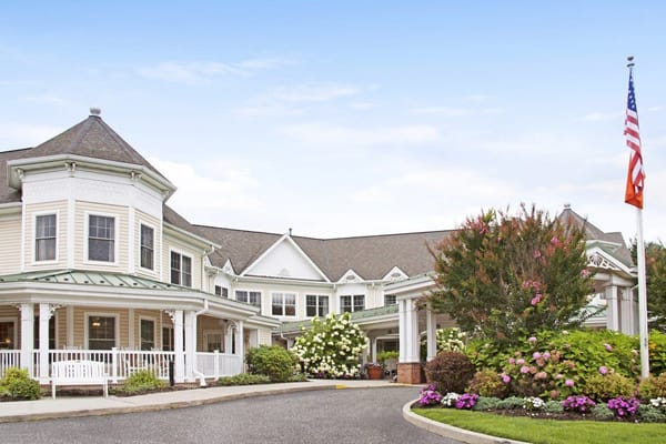 Entrance of Sunrise of Dix Hills senior living facility with landscaped gardens