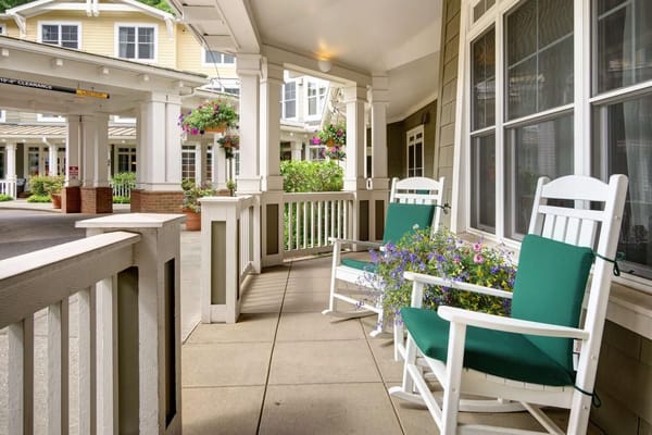 Two rocking chairs on a porch with purple flowers.