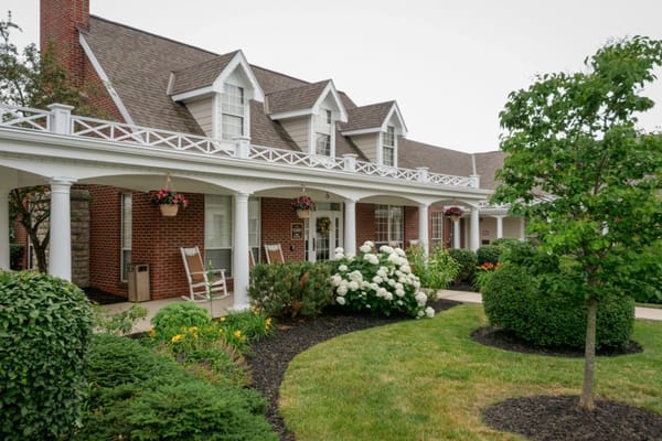 Exterior view of a senior living facility entrance with gardens