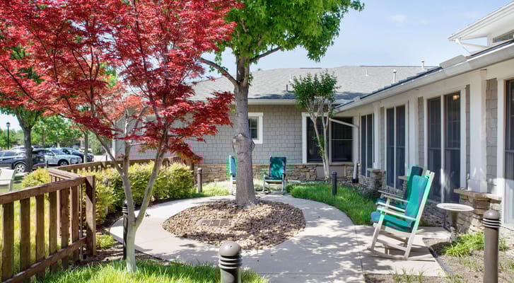 A serene garden path with seating and vibrant trees at Sunrise of Fort Worth.