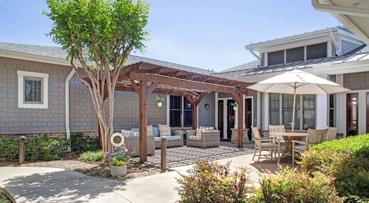 Cozy outdoor lounge with comfortable seating and a dining area under an umbrella.