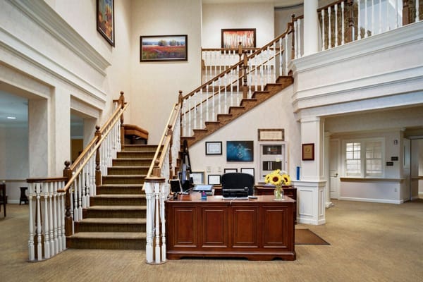 Warm reception area with a staircase and wooden front desk.