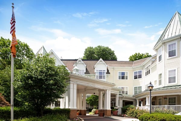 Front entrance of Sunrise of Haverford with greenery and flag