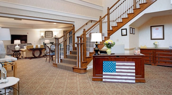 The welcoming lobby of Sunrise of Holbrook featuring a staircase and seating area.