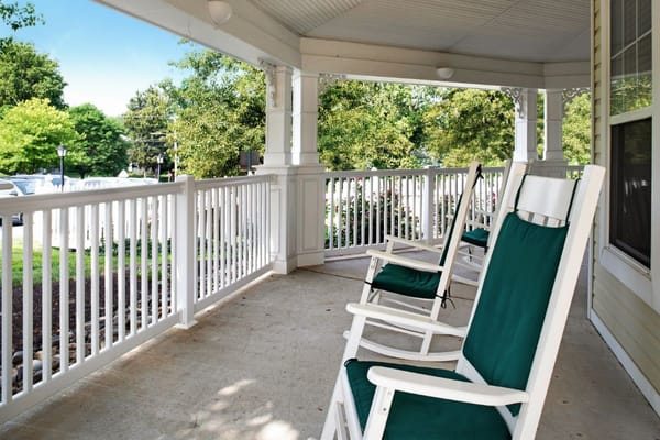 Rocking chairs on a porch with greenery in the background