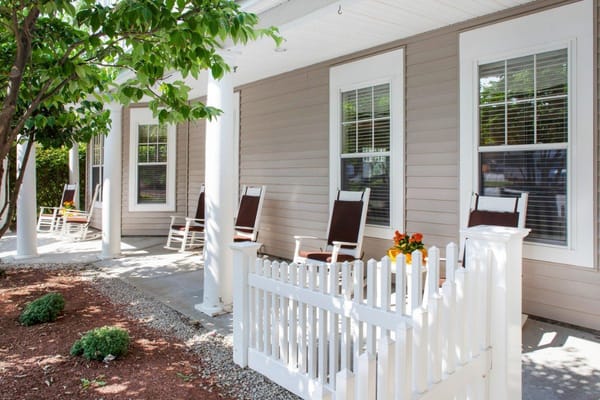 Porch with rocking chairs and a flower pot at Sunrise of Leominster.