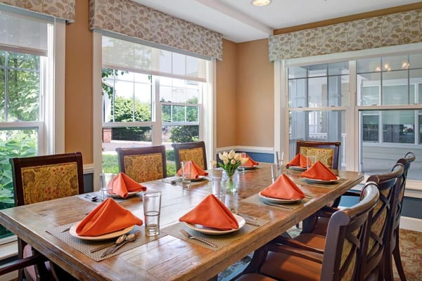 A beautifully set dining table with orange napkins at Sunrise of North Wales.