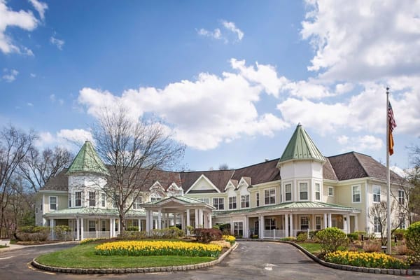 Front view of Sunrise of Old Tappan with blooming flowers and cloudy sky