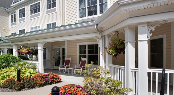 A sunny porch with rocking chairs surrounded by colorful flowers.