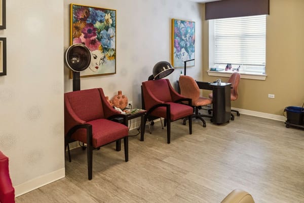 Cozy salon space with red and orange chairs and decorative artwork.