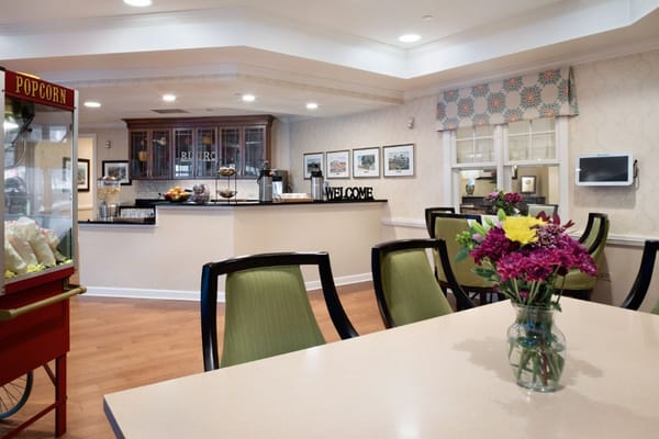 Bright common area with seating and floral arrangement at Sunrise of Willowbrook.