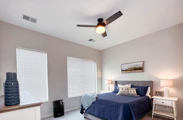 Spacious bedroom with a bed, two lamps, and large windows