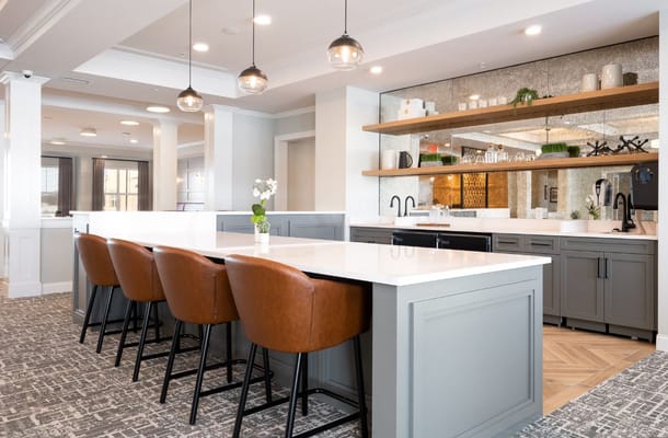 View of a modern kitchen bar with brown stools and a sleek countertop.