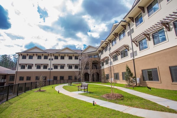 Exterior view of Tapestry House Assisted Living with walking paths and benches.
